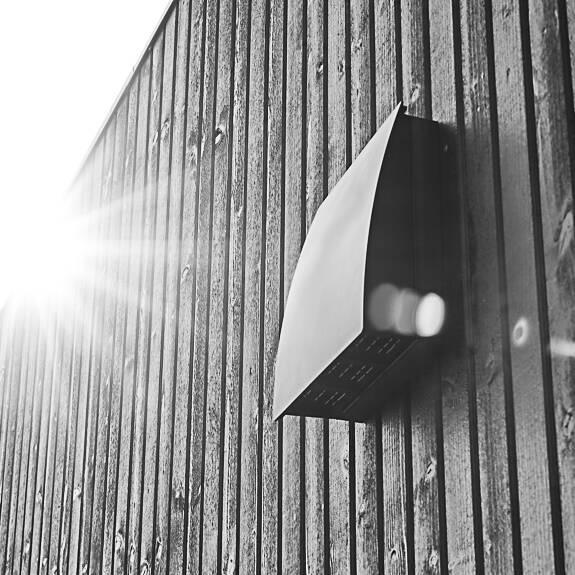 DUKA One DO 30 stormsköld i svart på distans placerad på en svart trävägg