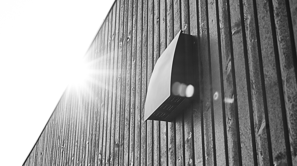 DUKA One DO 30 stormsköld i svart på distans placerad på en svart trävägg